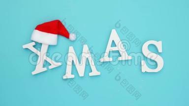 从红色圣诞老人帽的白色字母和蓝色背景雪蓝色背景。 概念圣诞快乐。 俯视图